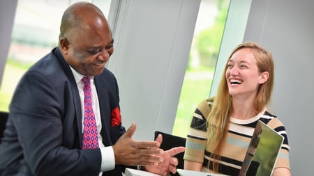 Smiling man in suit talking to laughing female student