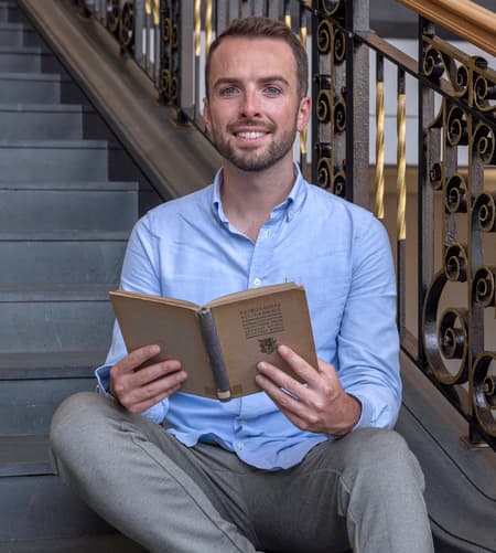 Smiling man sitting on steps and holding a book